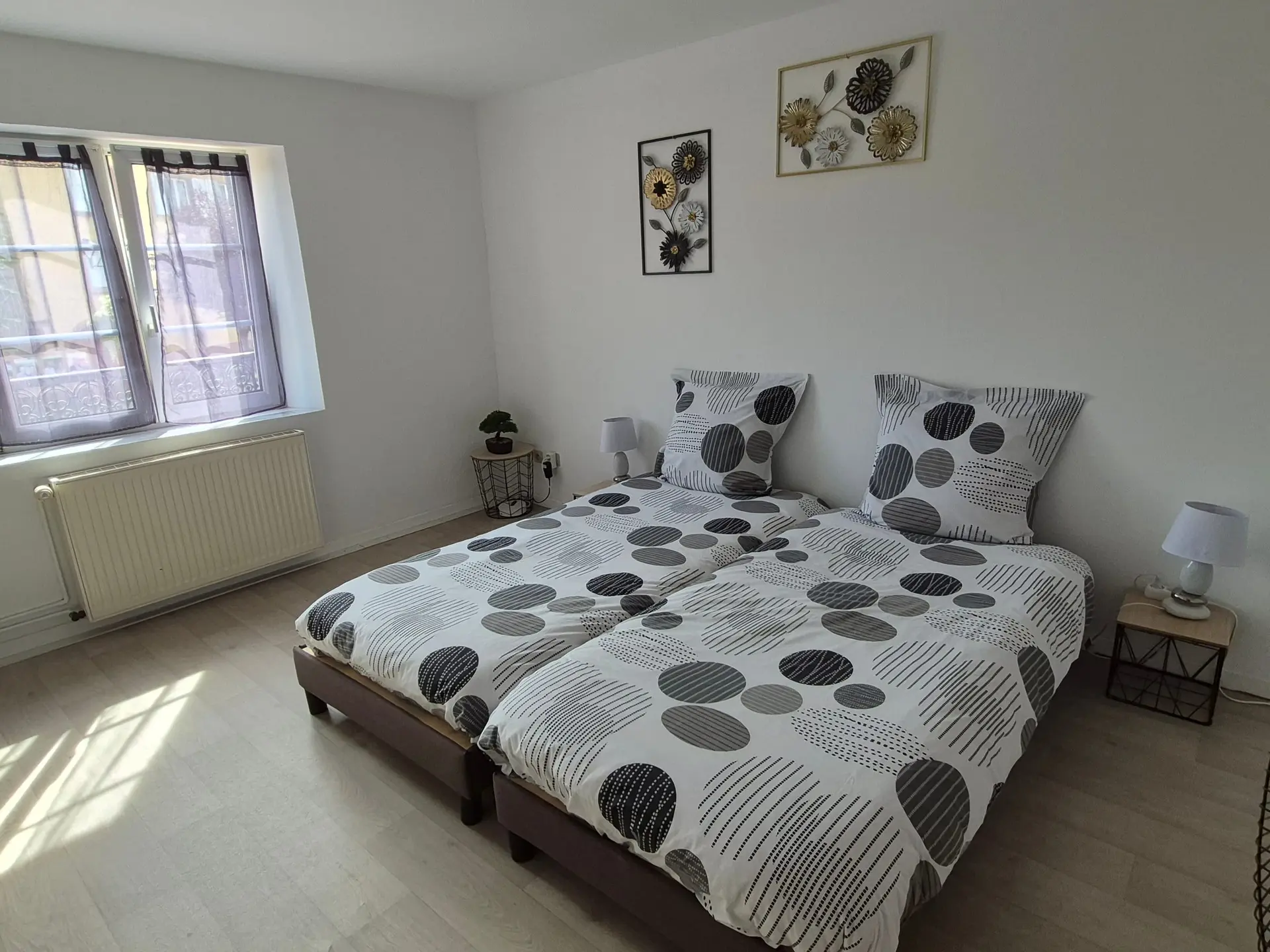 Seconde chambre avec deux lits simples côte à côte, parure blanche à pois gris.