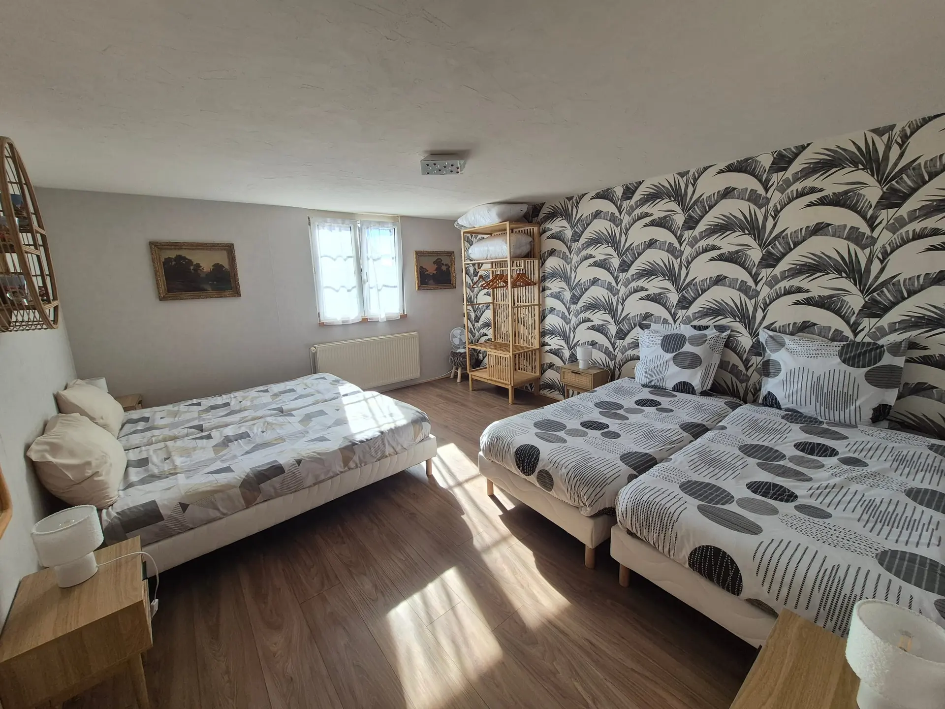 Grande chambre aux quatre lits simples réunis deux à deux, parures à pois et papier peint à feuillage.