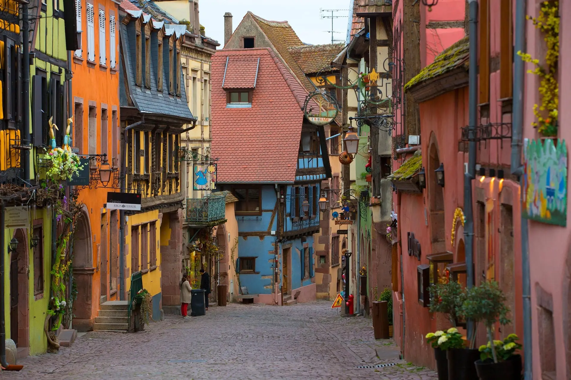 La rue pavée de Riquewihr, bordée de maisons à colombages aux couleurs vives.